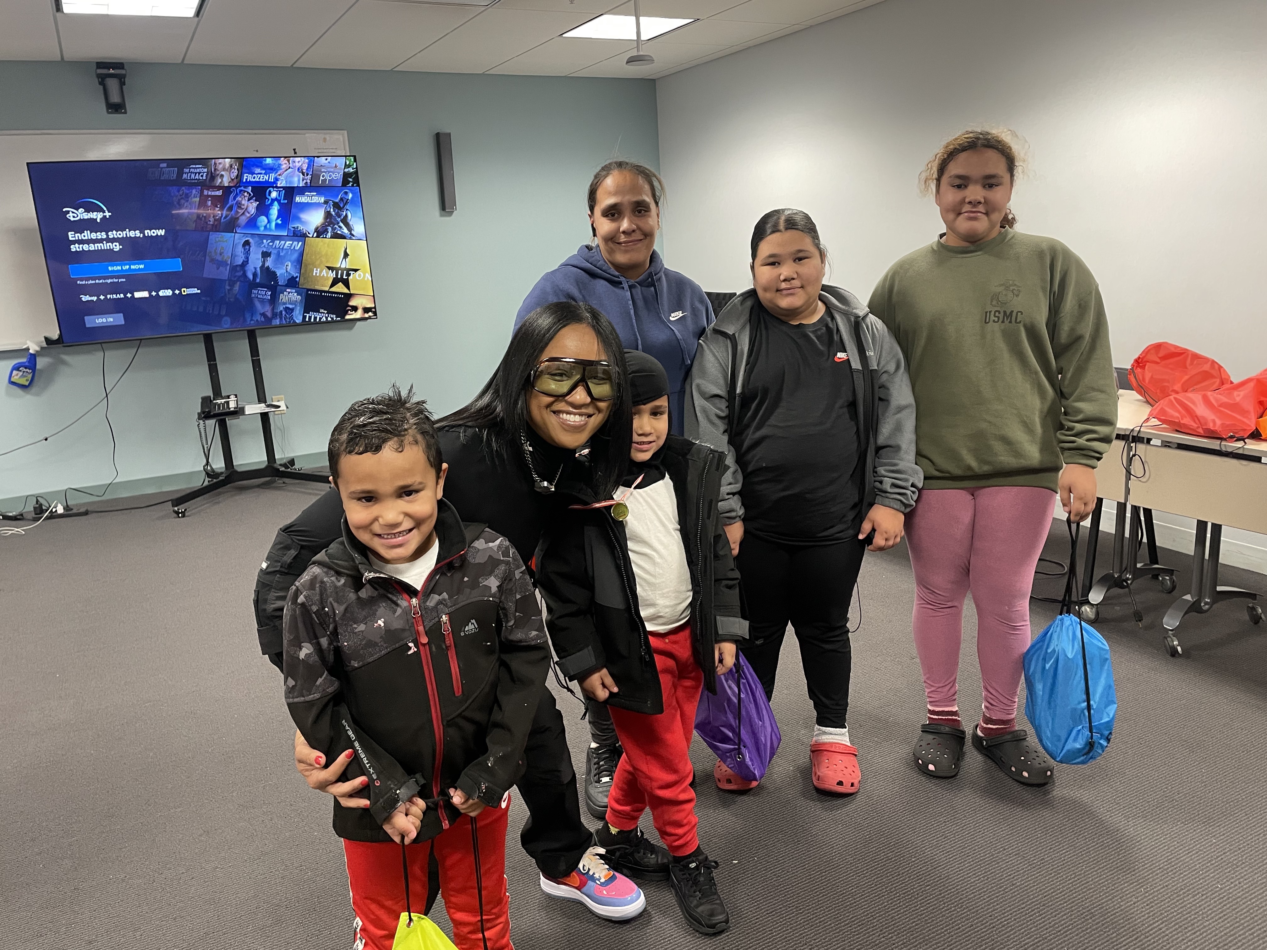Dalisha Pinto with a family at a giveaway, the children holding drawstring bags.