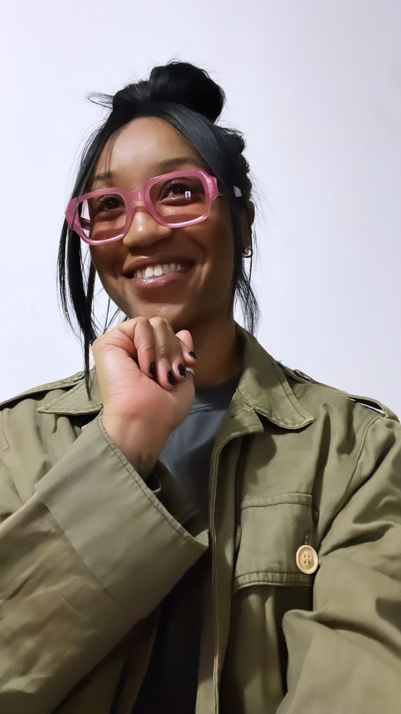 Dalisha Pinto, who founded Ladi Luck Foundation, smiling in pink glasses and an olive jacket.