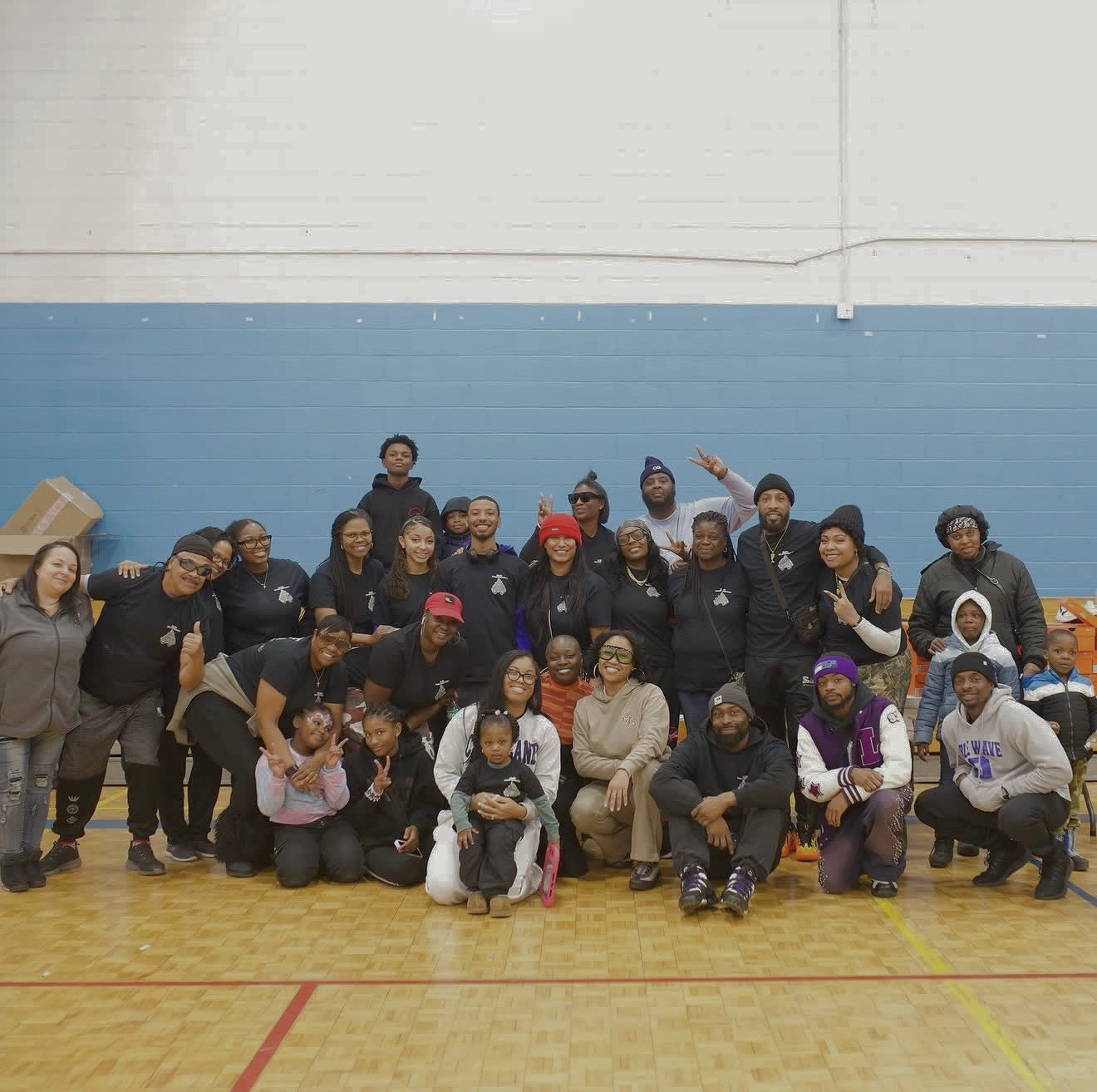 A large group of volunteers and families filling a school gym at a past giveaway.