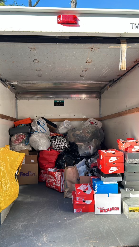 The back of a box truck loaded with bags and stacked shoeboxes, ready for a pickup run.